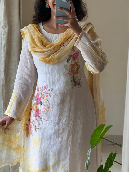 A0502 white & yellow tie dye mul chanderi 3 piece dress with hand paint & embroidery detailing comes with chiffon tie dye duppatta. The best part of this dress is at back part also you have same floral bunch detailing with hand paint & embroidery